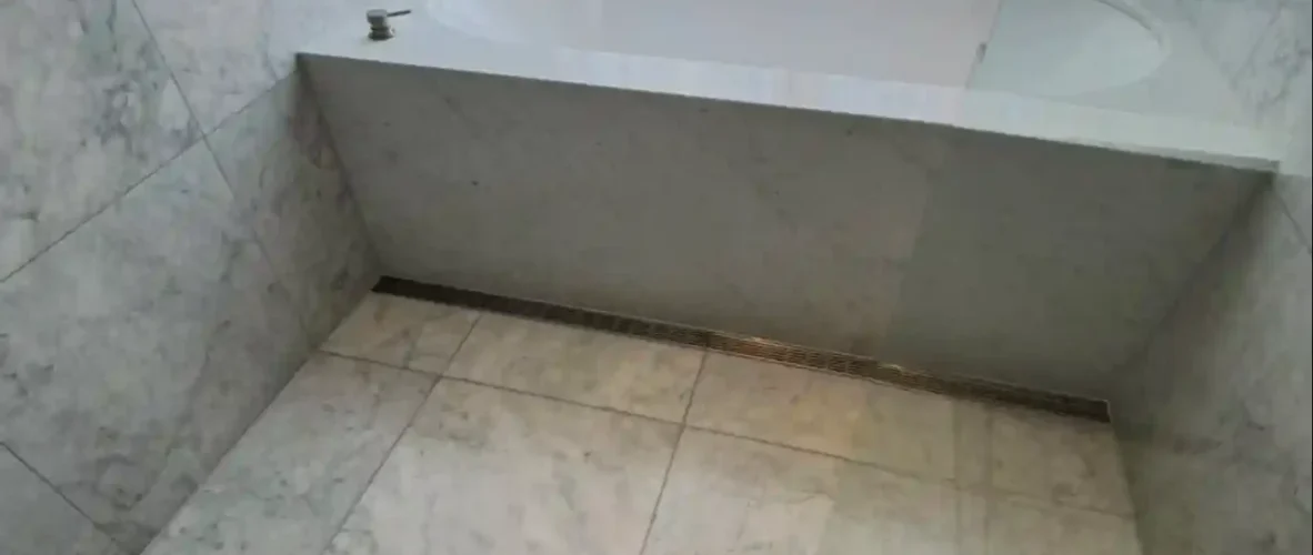 Marble bathroom with built-in bathtub needing repair.